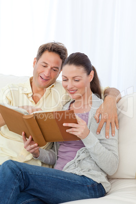 Cute couple looking at a photo album on the sofa