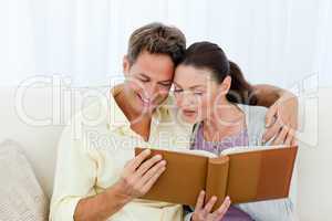 Attentive man and woman looking at a photo album on the sofa