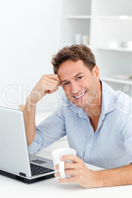 Portrait of man drinking coffee while working on his laptop