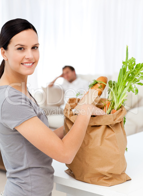 Happy woman with bags in the kitchen after shopping