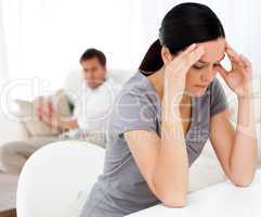 Man looking at his girlfriend having a headache sitting at a tab
