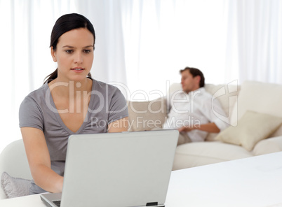Attentive woman working on the laptop while her boyfriend is sle