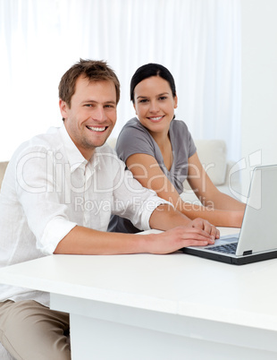 Portrait of a couple with a laptop at a table in the living room
