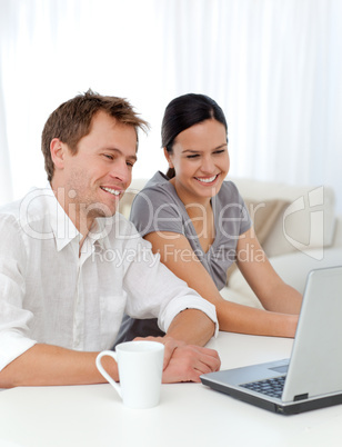 Lovely couple laughing while looking at a video on the laptop