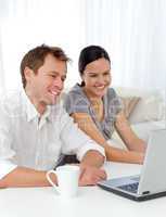 Lovely couple laughing while looking at a video on the laptop