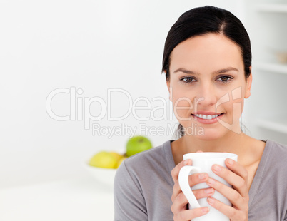Lovely woman holding a cup of coffee while relaxing in the kitch