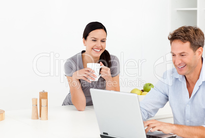 Cheerful couple looking at something on internet while drinking