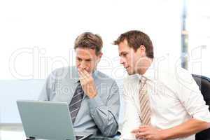 Two concentrated businessmen working together on a laptop