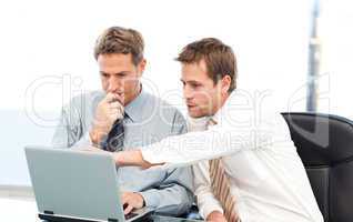 Two handsome businessmen working together on a project sitting a