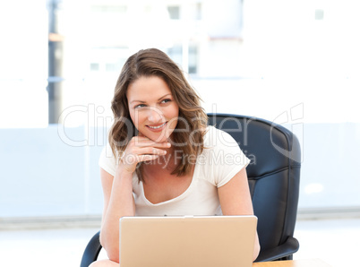Happy businesswoman working on laptop at a table