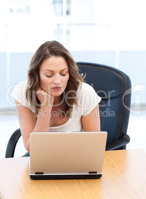 Thoughtful businesswoman working on laptop at a table