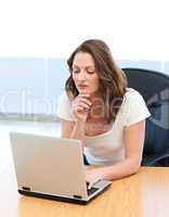 Pensive businesswoman working on laptop at a table