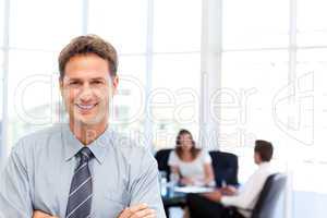 Proud businessman posing in front of his team while working