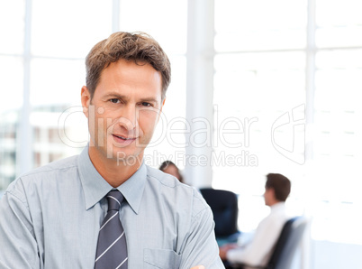 Severe businessman standing in front of his team while working a