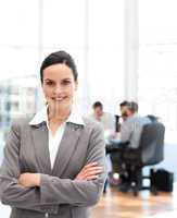 Cheerful businesswoman standing in front of her team while worki