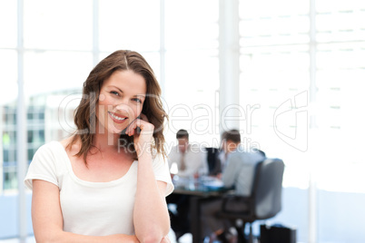 Cute businesswoman standing in front of her team while working