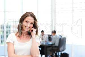 Cute businesswoman standing in front of her team while working
