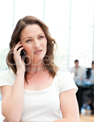 Pensive businesswoman on the phone while her team is working