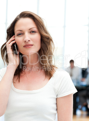 Confident businesswoman on the phone while her team is working