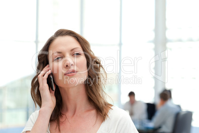 Attractive businesswoman on the phone while her team is working
