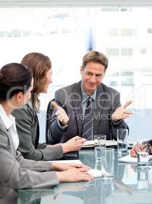 Happy manager talking to his team sitting at a table