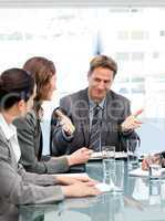 Happy manager talking to his team sitting at a table