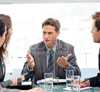 Severe manager talking to his team at a table