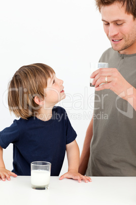 Little boy watching his father drinking milk