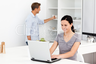 Cute woman working on the laptop in the kitchen