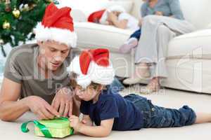Father and son unwrapping a present lying on the floor