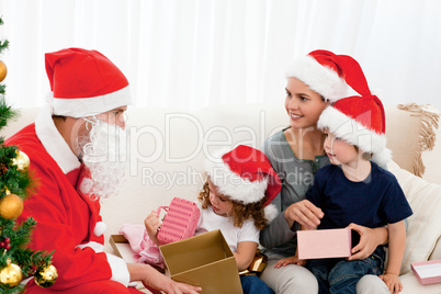 Santa giving presents to his children in the living room
