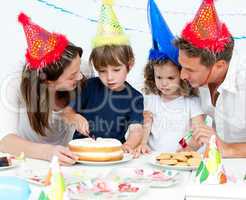 Cute little boy cutting a birthday cake for his family