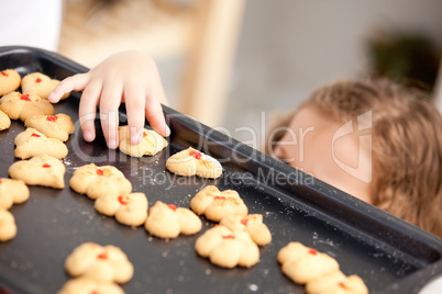 Close up of a little girl taking a cookie behind her mother's ba