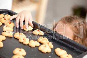 Close up of a little girl taking a cookie behind her mother's ba
