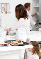 Cute little girl taking cookies while her parents are cooking