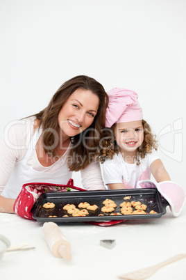 Adorable mother and daughter showing a plate with biscuits