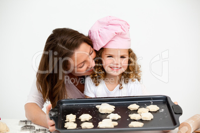 Happy little girl with her mother showing a plate with biscuits