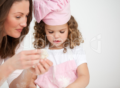 Glad mother and her daughter making biscuits together