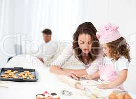Mother and daughter cooking while dad relaxing on the sofa