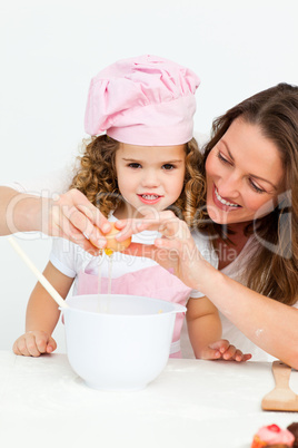 Mother showing her daughter how to break eggs