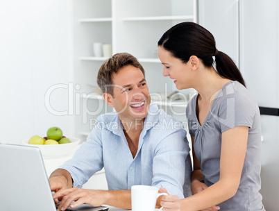 Happy couple working on their laptop in the kitchen