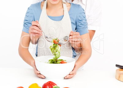 Close up of a man mixing a salad with his girlfriend