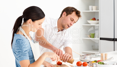 Man putting salt and pepper while his girlfriend stiring the sau