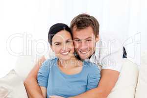 Portrait of a man hugging his girlfriend while relaxing on the s
