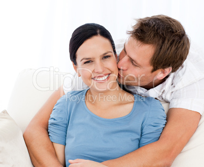 Lovely man kissing his girlfriend while relaxing on the sofa