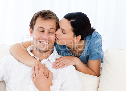 Lovely woman kissing her boyfriend while relaxing on the sofa