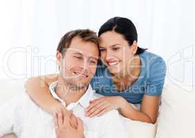 Lovely woman hugging her boyfriend while relaxing on the sofa