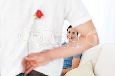 Attentive man hidding a flower behind his back for his girlfrien