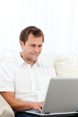 Happy man working on his laptop on the sofa