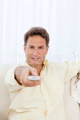 Relaxed man pointing a remote to the camera